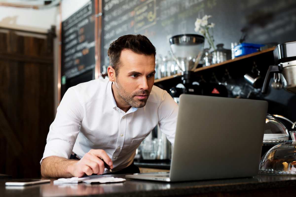 Man in a white shirt at a coffee shop working with his computer